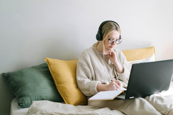 Female creative entrepreneur writing in her planner sat on sofa